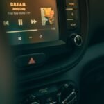 Close-up of a car dashboard featuring a modern stereo system playing music.
